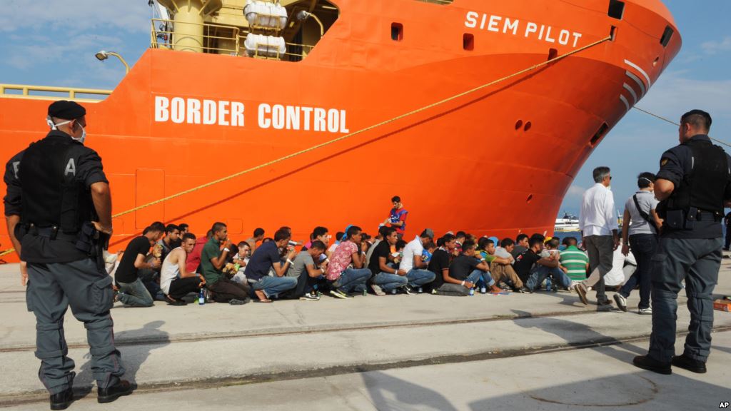 Rescued migrants line up after disembarking from the Norwegian cargo ship Siem Pilot at the Reggio Calabria's harbor Italy Aug. 8 2015