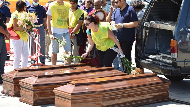 Volunteers lay flowers on coffins with the bodies of migrants after they were disembarked from LE Niamh a Roisin Class large patrol vessel of the Irish Naval Service at the Messina harbor in Sicily Italy | AP