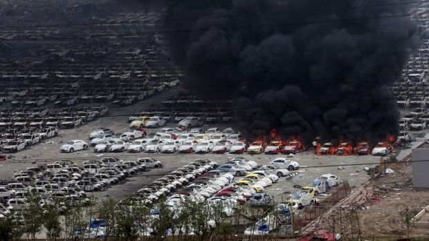 Smoke rises as damaged vehicles are seen burning near the site of Wednesday night's explosions