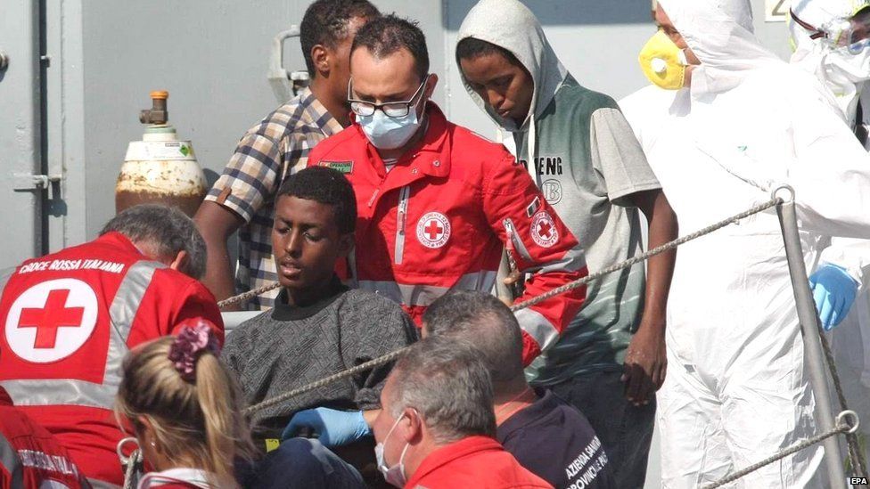 Members of the crew of the Irish Naval vessel the LE Niamh and members of the Italian Red Cross help some 300 migrants as they arrive in Palermo Italy on 6 August 2015