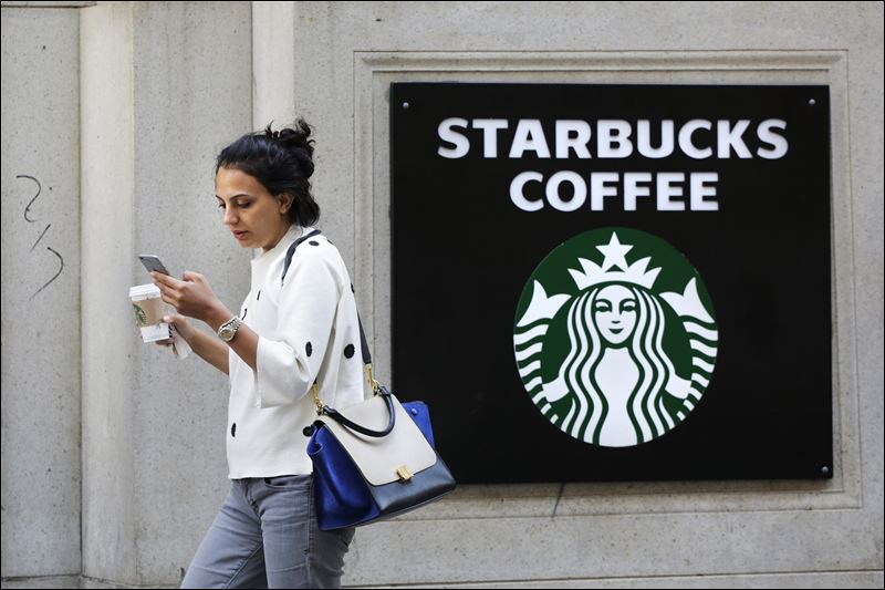 A woman walks out of a Starbucks Coffee with a beverage in hand in New York