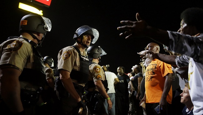 Officers and protesters face off along West Florissant Avenue on Monday night in Ferguson Missouri. Ferguson was a community on edge again Monday a day after a protest marking the anniversary of Michael Brown’s death was punctuated with gunshots. (Jef