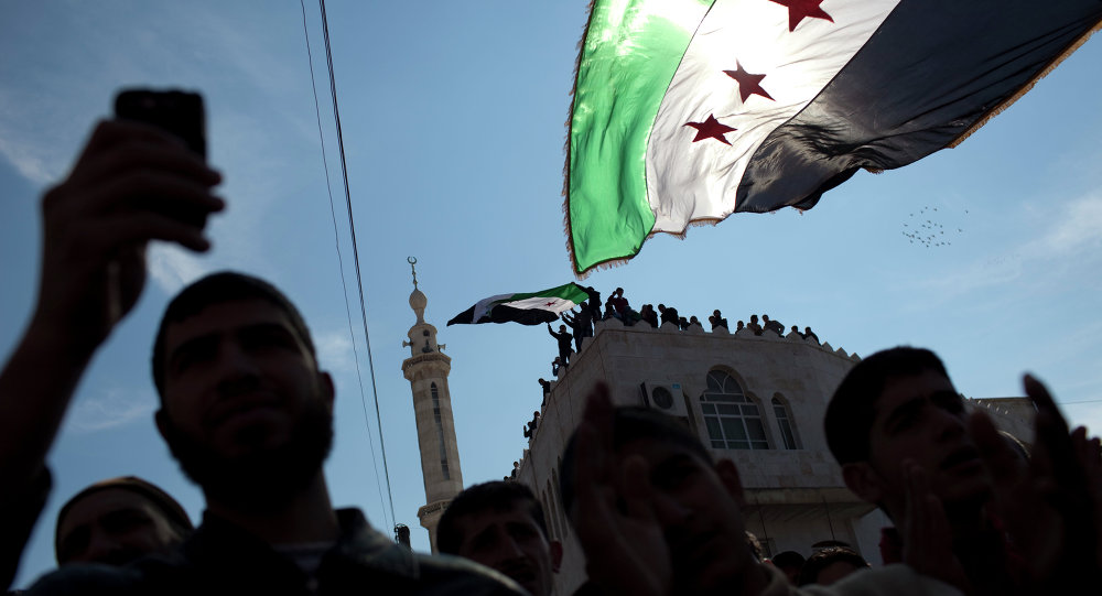 Men hold revolutionary Syrian flags during an anti-government protest in a town in northern Syria