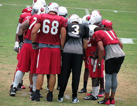 The Arizona Cardinals huddled during a pre-season workout to discuss strategy. Fans are huddling to pray for a Super Bowl this year