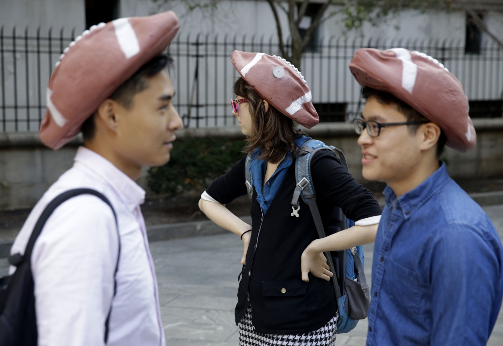 People wearing hats in the shape of deflated footballs gather outside a federal courthouse in New York Wednesday Aug. 12 2015. New England quarterback Tom Brady and NFL Commissioner Roger Goodell are set to explain to a judge why a controversy over und