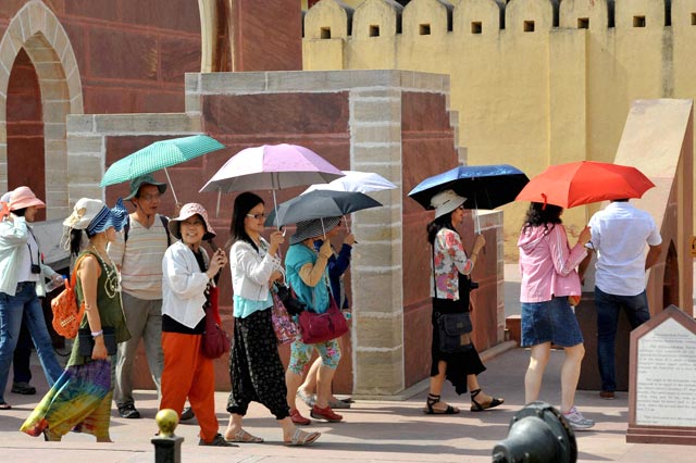 Tourists hold umbrellas as they visit