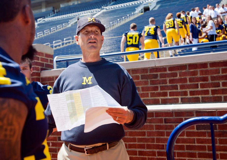 Michigan head coach Jim Harbaugh coordinates his players to lineup in the Michigan Stadium stands for a team