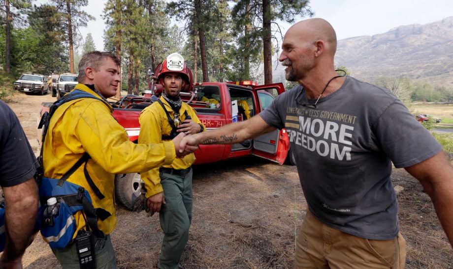 Homeowner Brad Craig right thanks departing firefighters who he said saved his home from a wildfire Saturday morning Aug. 22 2015 in Okanogan Wash. Craig said that the team of firefighters saved his home from burning down after he saw flames advanci