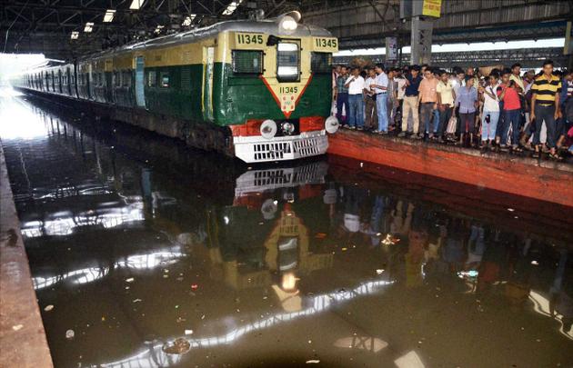 Waterlogged railway tracks at Sealdah Station runway at the airport a hand rickshaw puller wading through a street and a man helps his companion cross a street in Kolkata on Saturday after heavy rain lashed the city