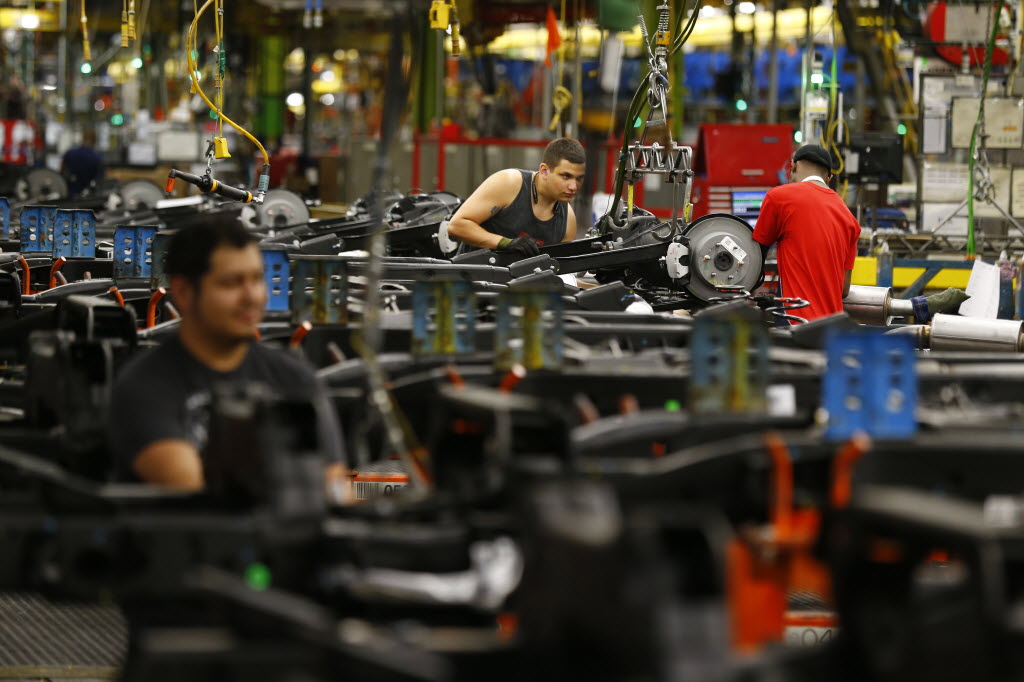 Workers attach brake components to SUV chassis at the GM Arlington plant