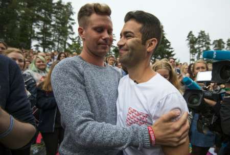 Labour Party youth leader Mani Hussaini is hugged by his predecessor Eskil Pedersen at the start of a summer camp on the Norwegian island of Utoya