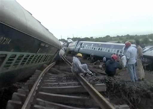 In this image made from video people gather by the twisted track alongside two derailed trains in Harda in Madhya Pradesh state India Wednesday Aug. 5 2015. Two passenger trains derailed over a bridge in central India while crossing a track that was