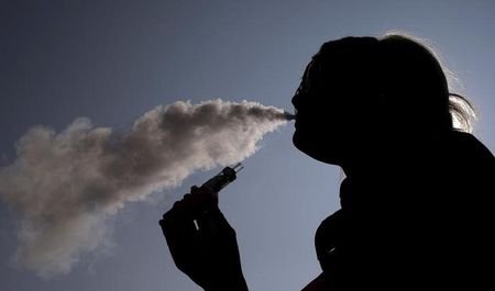 A woman exhales vapour from an e-cigarette