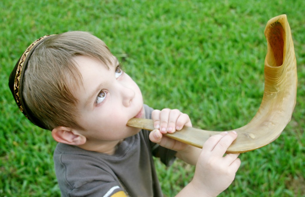 A young boy blows a shofar for the Jewish holiday Rosh Hashana