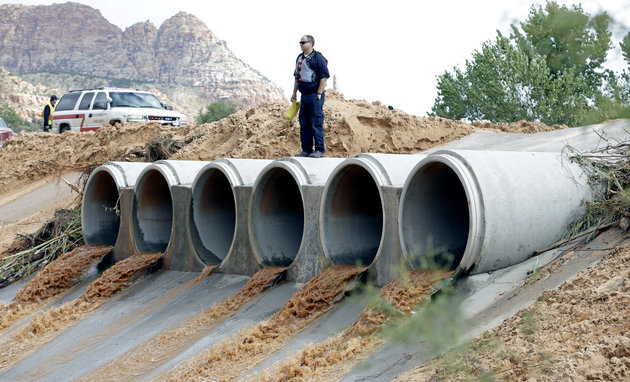 A search-and-rescue worker looks down a spillway along a steam after a flash flood on Sept. 15 2015 in Colorado City Arizona. A wall of water swept away vehicles in the Utah Arizona border town killing several people