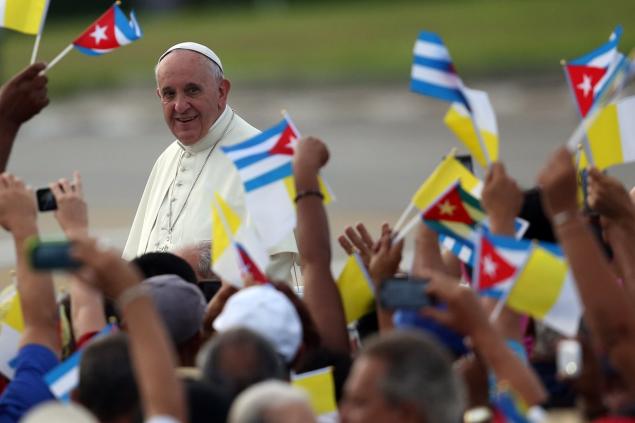 People wave Cuban and Papal flags as Pope Francis arrives to perform Mass in Revolution Square in Havana on Sunday