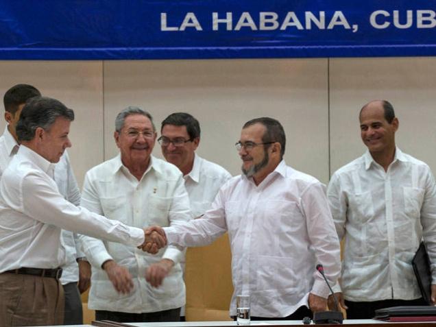 Cuba's President Raul Castro center smiles as Colombian President Juan Manuel Santos center left and Commander the Revolutionary Armed Forces of Colombia or FARC Timoleon Jimenez known