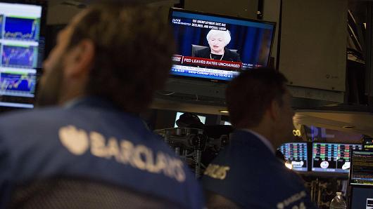 Traders work as Janet Yellen chair of the U.S. Federal Reserve is seen speaking on a television screen on the floor of the New York Stock Exchange in New York U.S. on Thursday Sept. 17 2015