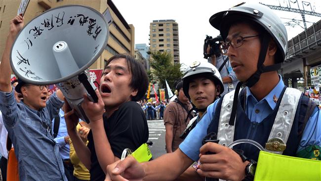 Police officers try to hold back demonstrators attempting to stop a vehicle transporting members of the parliament’s upper house security bills committee in suburban Tokyo