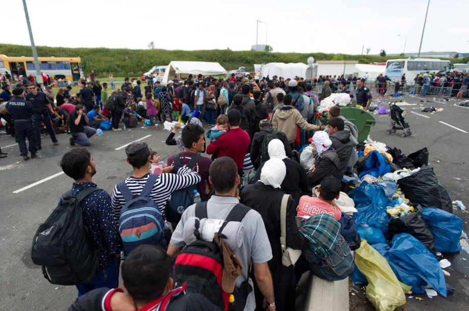 Refugees wait for buses after crossing the Austrian — Hungarian border near Heiligenkreuz Austria on Monday. The United States should help carry the load by accepting Syrian refugees