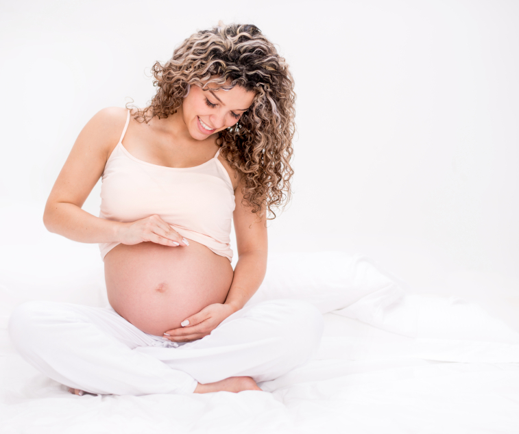 Pregnant woman sitting on the floor stroking her belly