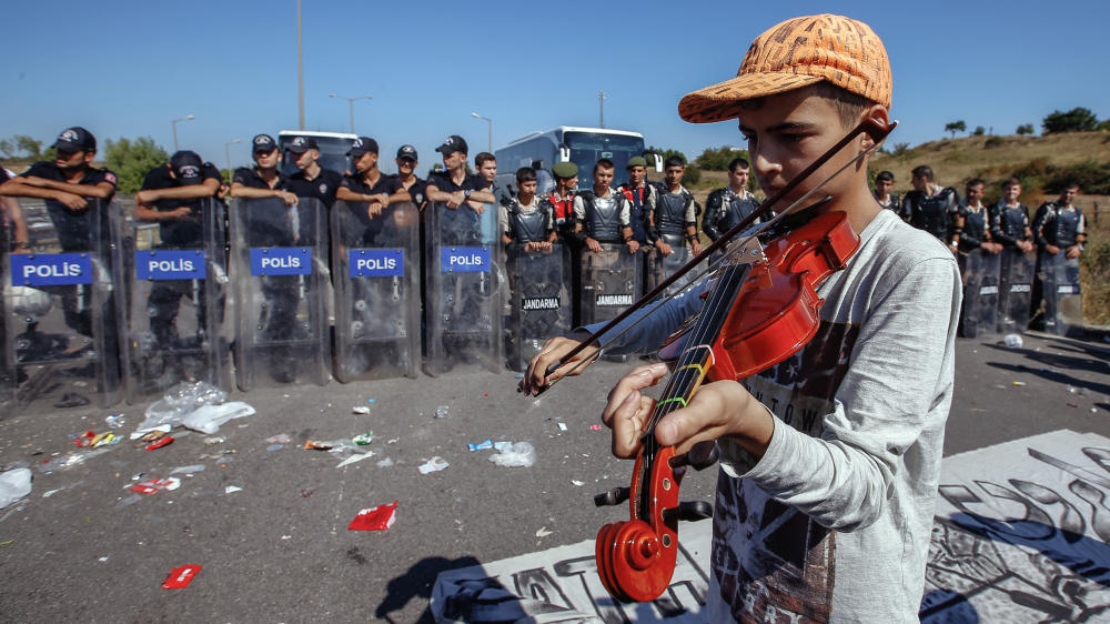 A refugee boy plays a violin as hundreds of migrants are blocked from marching down a highway toward Turkey's western border with Greece and Bulgaria on Saturday. Turkey has some 2 million refugees mostly from Syria but says they will not be allowe