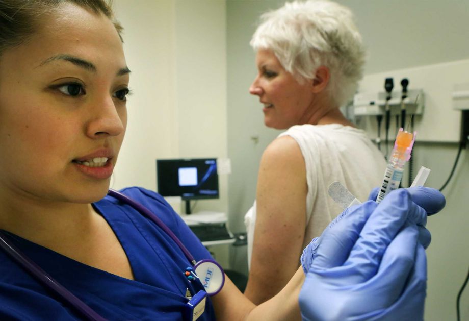 Sasha Rios left a medical assistant at Primary Care Clinic of UT Medicine San Antonio prepares to administer a flu shot to Erin Spitz on Wednesday