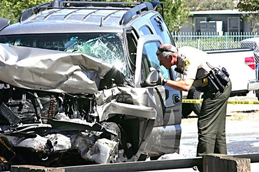 A deputy checks an SUV involved in a crash on Interstate 215 at the Little League Drive freeway overpass in San Bernardino Calif. Friday Sept. 18 2015. Authorities say a wrong-way freeway driver has died in California after being shot at from a San Be