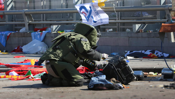 A bomb disposal officer inspects a suspected suitcase that proved to be empty at the scene of an explosion in Ankara Turkey. Image AP