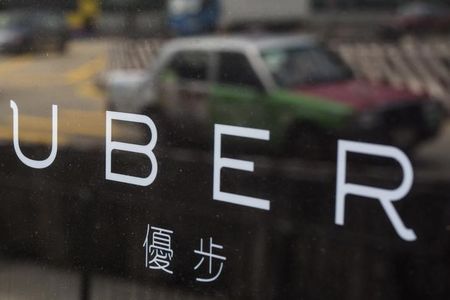 A taxi is reflected in a window at the office of taxi-hailing service Uber Inc in Hong Kong China