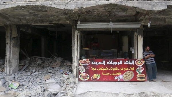 A vendor stands near his fast food shop amid rubble in Aleppo Syria Oct. 13 2015