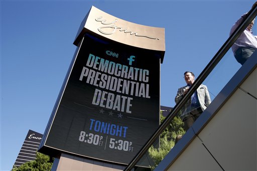 Members of the public walk under a billboard promoting the CNN Democratic presidential debate Tuesday Oct. 13 2015 in Las Vegas. Democratic presidential candidates Hillary Rodham Clinton Jim Webb Bernie Sanders Lincoln Chafee and Martin O'Ma