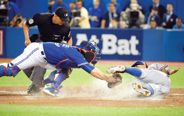 Texas Rangers’ second baseman Rougned Odor scores a run past the tag of Toronto Blue Jays’ catcher Russell Martin during Game 2 of the ALDS at Rogers Centre in Toronto Friday. — Reuters