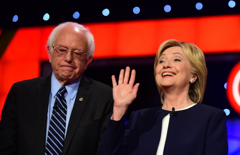 Presidential hopeful Hillary Clinton gestures while standing beside Bernie Sanders during