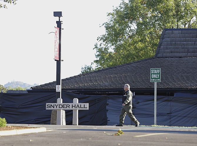 A Douglas County Sheriff's deputy walks past Snyder Hall at Umpqua Community College Sunday Oct. 4 2015 in Roseburg Ore. Armed with multiple guns suspect Chris Harper Mercer walked into a class at Snyder Hall on Thursday killing nine and wound