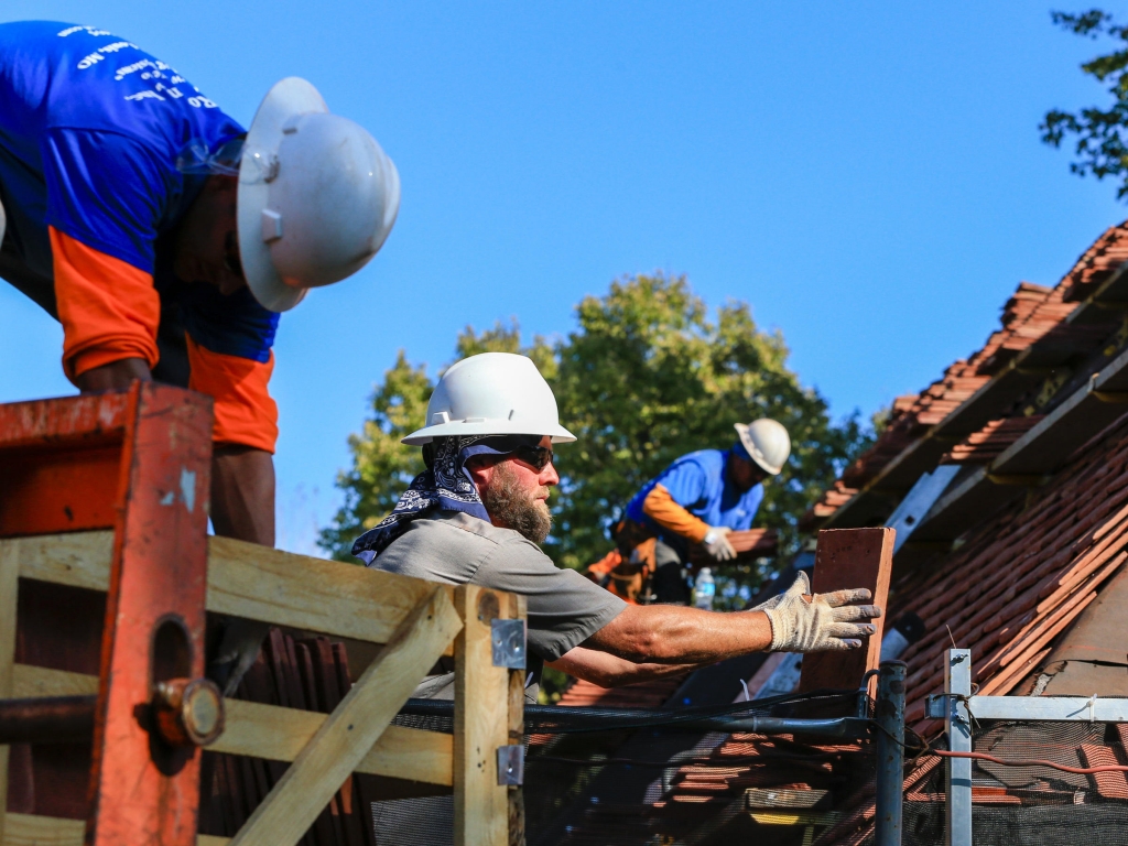 Construction workers lay tiles on the roof of a house in Boys Town Nebraska