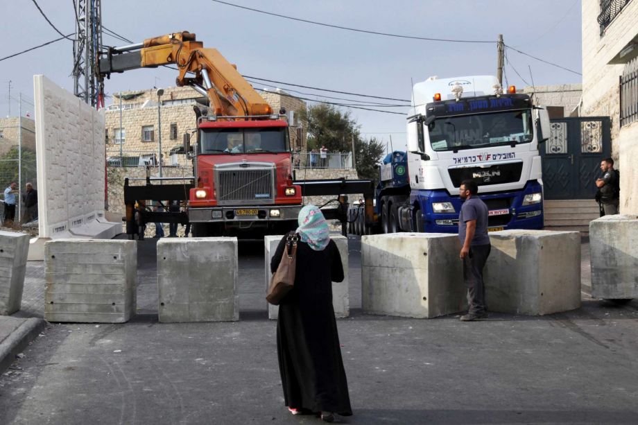 Palestinians watch a wall being built between Palestinian and Jewish neighborhoods in Jerusalem Sunday Oct. 18 2015. Palestinians in Jerusalem more than one-third of the city's population have awoken to a new reality Israeli troops are encircling Ar