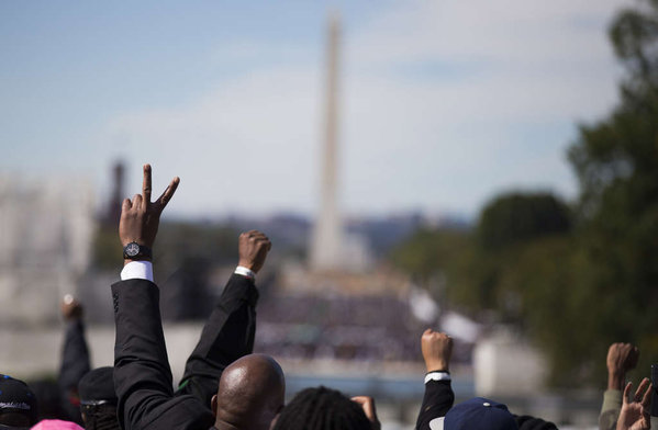 People raise their arms as they mark the 20th anniversary of the Million Man March in Washington. Saturday´s event reflected the growing anger and tension over recent killings by police