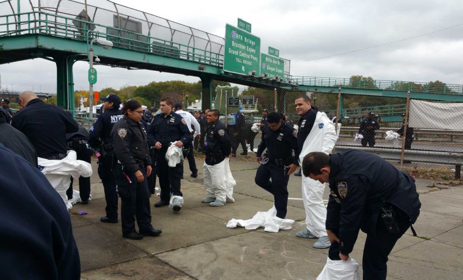 CORRECTS FIRST NAME OF SLAIN OFFICER TO RANDOLPH NOT RUDOLPH- NYPD officers remove white suits worn to protect against contaminating evidence during a ground search near the scene where earlier in the morning a gun was recovered from the Harlem River