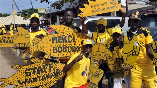 Supporters of Guinea’s President Alpha Conde and presidential candidate hold placards reading “Thank you Bobody” and “Staff Wantanamo” during a presidential election campaign in Conakry