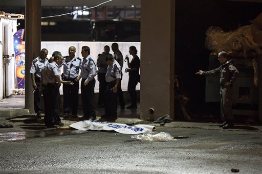 Israeli police stand by the shrouded body of Palestinian attacker in Beersheba Israel Sunday Oct. 18 2015. An Arab attacker armed with a gun and a knife opened fire in a southern Israel bus station on Sunday police said killing an Israeli soldier