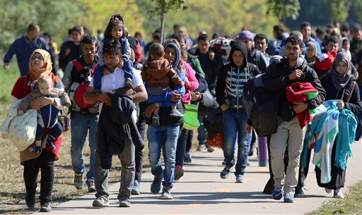 Migrants walk to the border between Hungary and Austria in Hegyeshalom Hungary Thursday Oct. 1 2015. The European Union is threatening to take action against Hungary over laws it has introduced to limit the flow of migrants through its territory. (AP