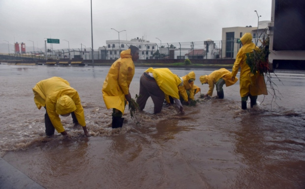 Workers clear branches from a flooded street in Manzanillo