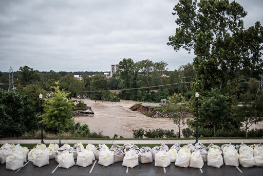 Flood waters rush through the breach of the Columbia Canal as emergency workers prepare giant sandbags to plug the hole on Oct. 5 2015 in Columbia S.C