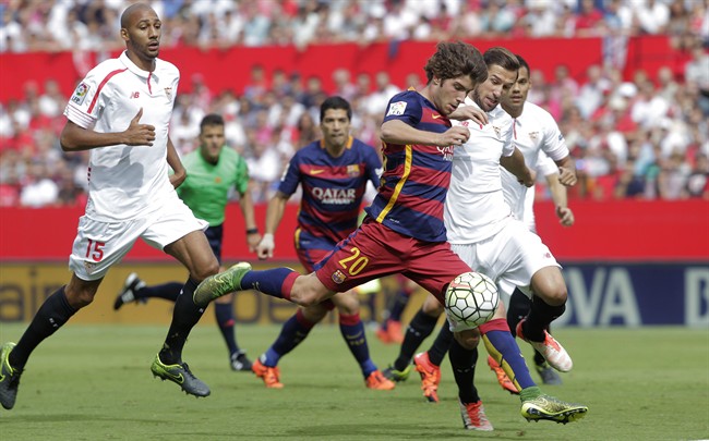 Barcelona's Sergi Roberto second right and Sevilla's Grzegorz Krychowiak right vie for the ball during their La Liga soccer match at the Ramon Sanchez Pizjuan stadium in Seville Spain on Saturday Oct. 3 2015