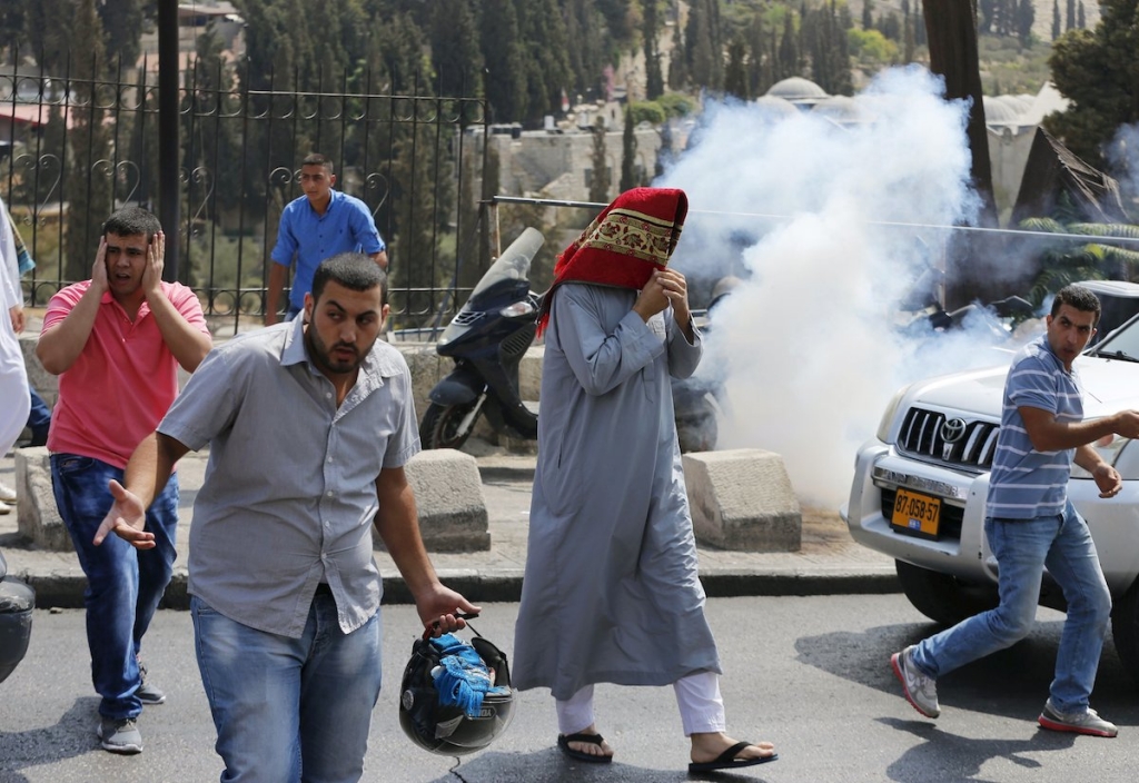 A Palestinian man covers his head with a prayer mat as smoke from a stun grenade fired by Israeli policemen disperses during clashes near the East Jerusalem neighbourhood this week. – Reuters pic