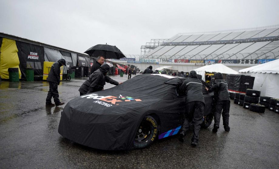 Crew members push the race car of Denny Hamlin in the garage area for the NASCAR Sprint Cup series auto race Friday Oct. 2 2015 at Dover International Speedway in Dover Del