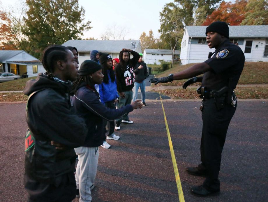 'Wait for the facts to come out' a Normandy police officer tells a group of men Wednesday Oct. 28 2015 at the edge of crime scene tape blocking off access to the 7700 block of Ellington Dr. in Normandy Mo. Authorities say a St. Louis-area officer