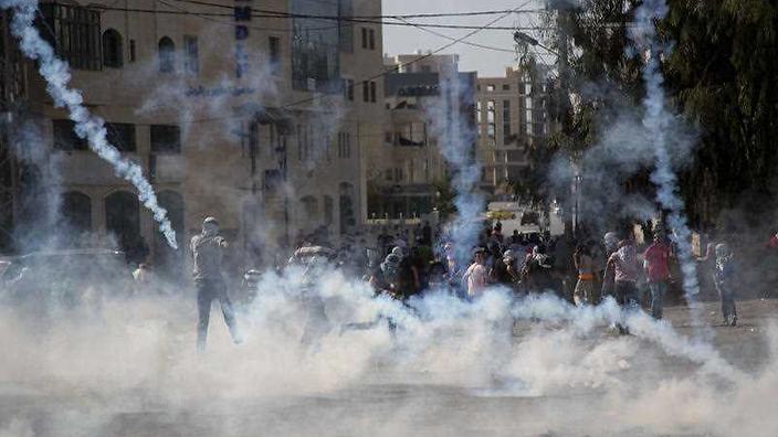 Palestinian protesters run for cover from tear gas fired by Israeli soldiers during clashes with Israeli troops near Ramallah West Bank