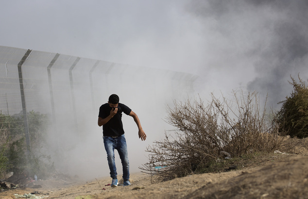 A Palestinian protester runs for cover from tear gas fired by Israeli soldiers during clashes on the Israeli border with Gaza east of Bureij refugee camp